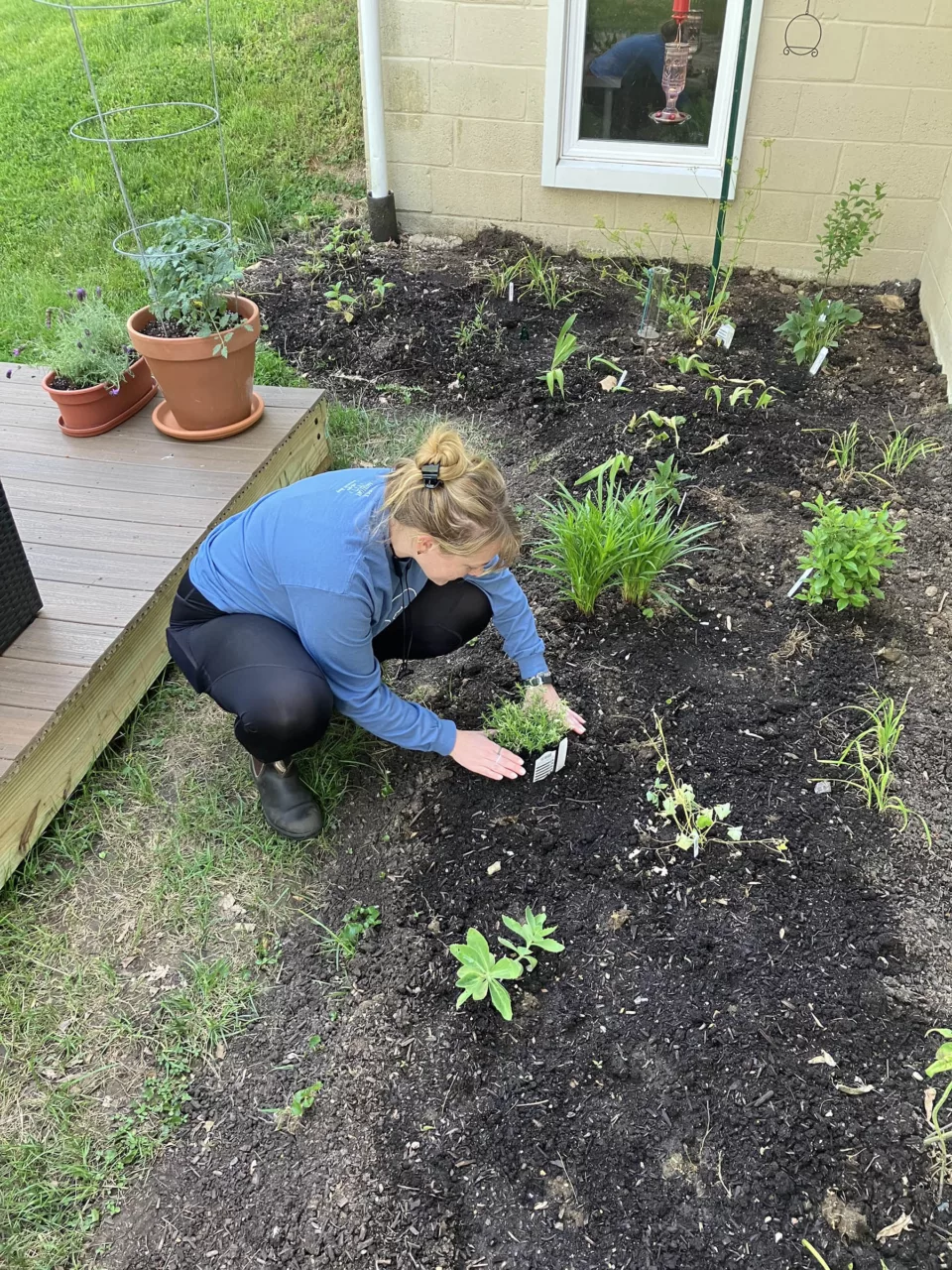 A woman planting in a garden bed.
